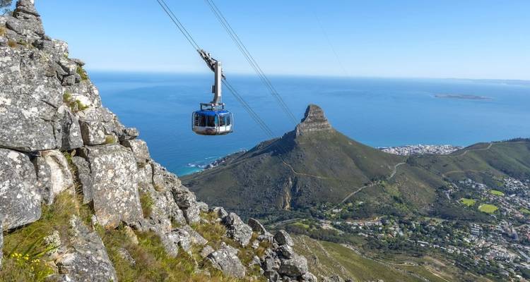 Un téléphérique qui monte une montagne avec vue sur l'océan.
