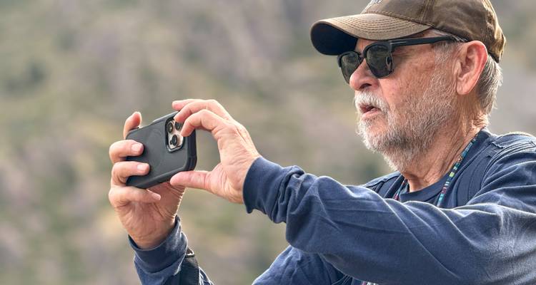 Personne tenant un smartphone prenant une photo à l'extérieur.