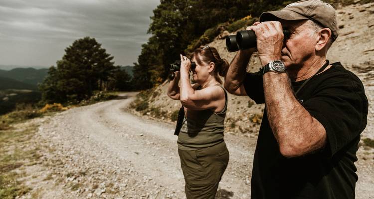 Homme et femme utilisant des jumelles sur un sentier de montagne.