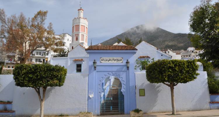 Weißes Gebäude mit einer blauen Tür und Bergkulisse