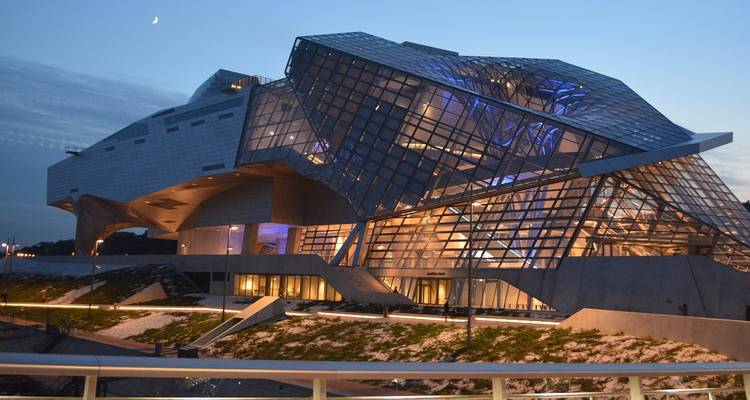 Bâtiment contemporain du Musée des Confluences en verre et acier illuminé de lumières bleues au crépuscule