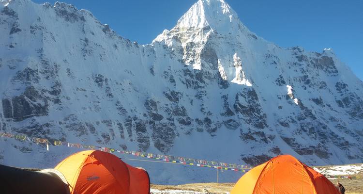 Tentes dressées devant de majestueuses montagnes enneigées.