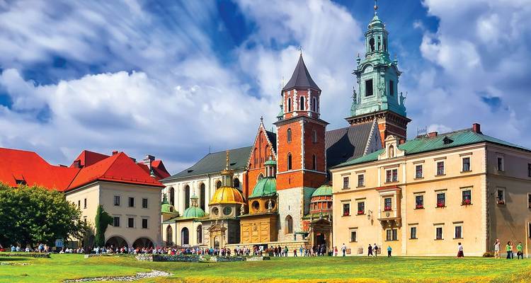 Wawel Castle complex in Krakow with colourful rooftops and crowds of visitors gathered on the grassy lawn