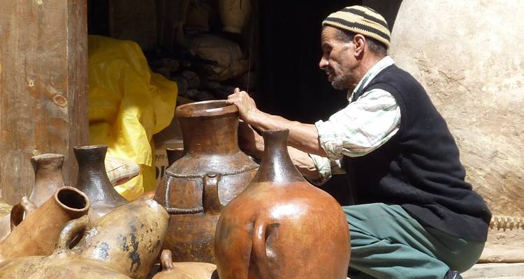 Persona organizando ollas tradicionales en un entorno cultural.