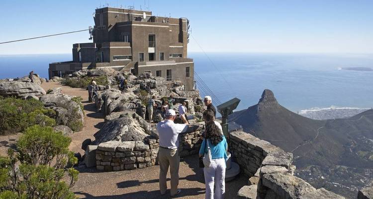 Touristes prenant des photos sur une montagne avec vue sur l'océan.