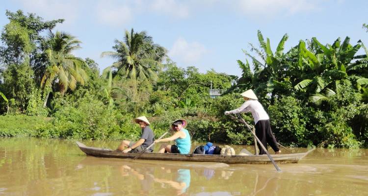 Small boat navigating a river surrounded by lush greenery.