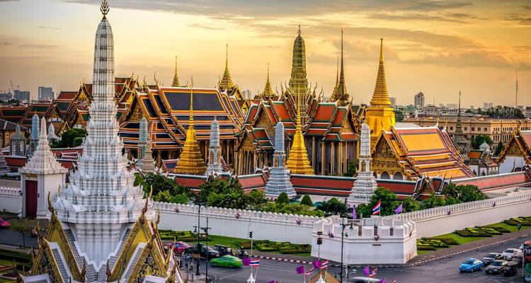 Het Grote Paleis in Bangkok met gouden torenspitsen bij zonsondergang.