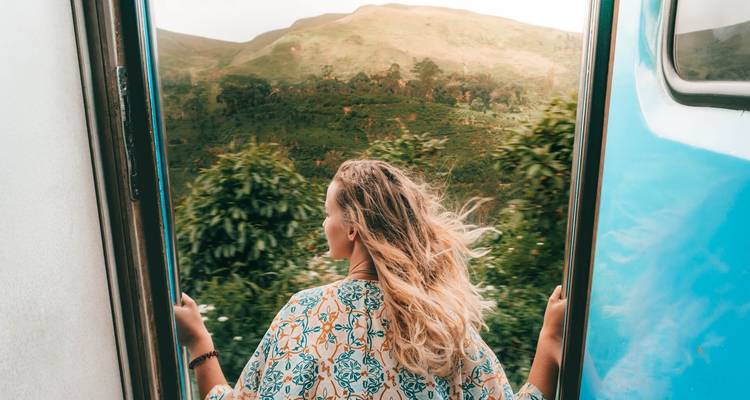 Jeune femme voyageant en train avec ses cheveux qui flottent au vent.