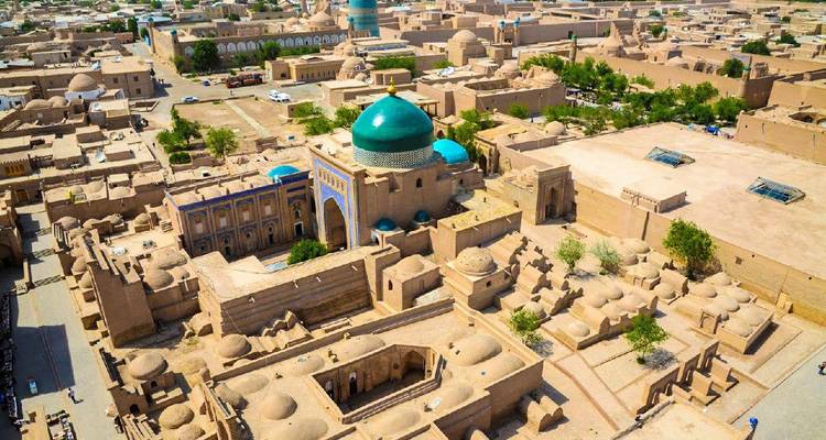 Vista aérea de un pueblo antiguo de ladrillos de barro con una mezquita de cúpula turquesa en su centro