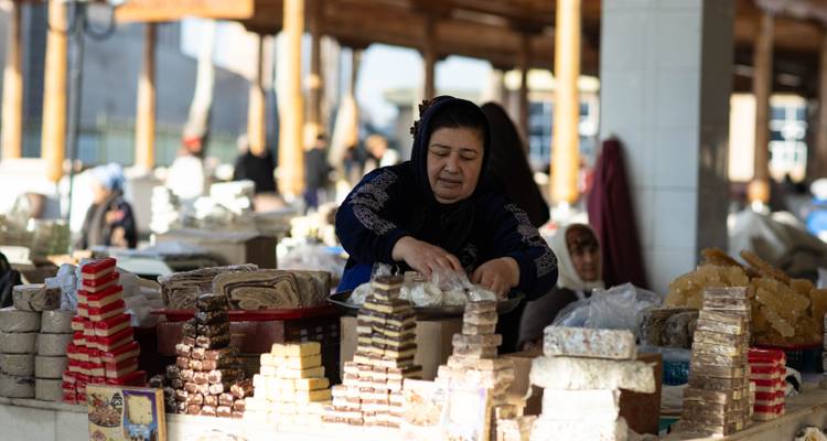 Vendedor arreglando dulces tradicionales en un mercado cubierto concurrido