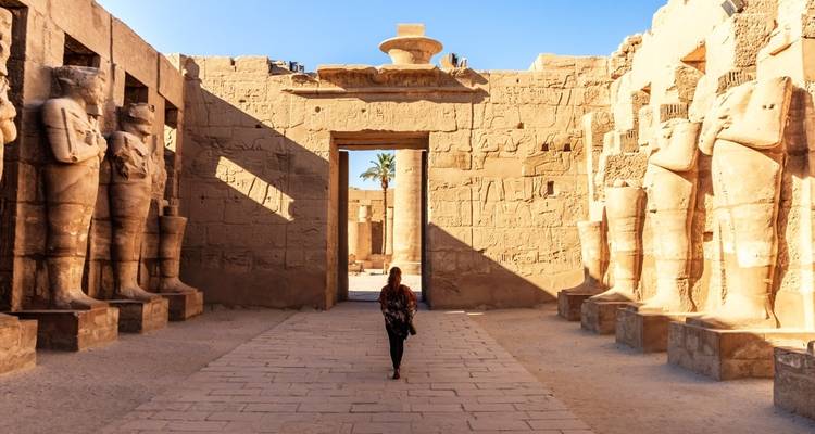 Un temple égyptien antique avec une personne qui marche à travers.