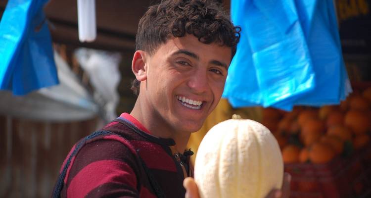 Persona sonriendo y sosteniendo un melón en un mercado