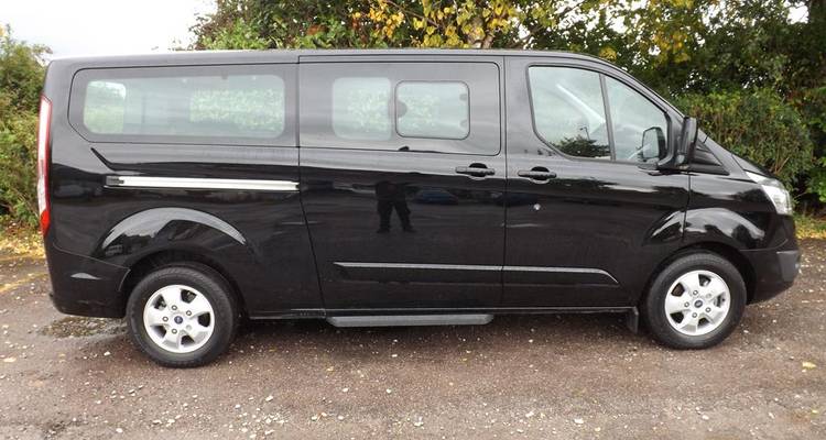 Zwarte bestelwagen geparkeerd op een open terrein.