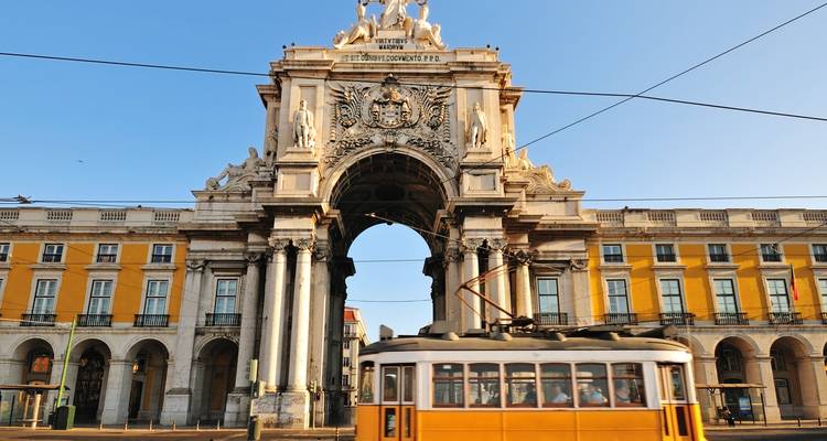 Arco de la Rua Augusta en Lisboa con un tranvía amarillo pasando por debajo.