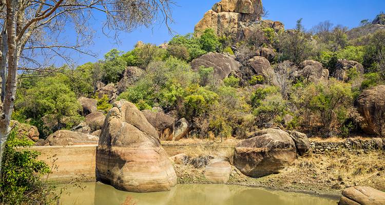 Scenic landscape with rocky outcrops and water pool.