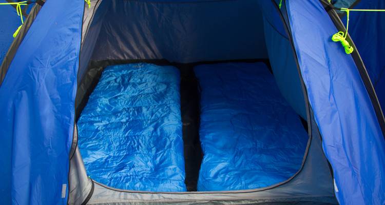 Intérieur d'une tente bleue avec des sacs de couchage