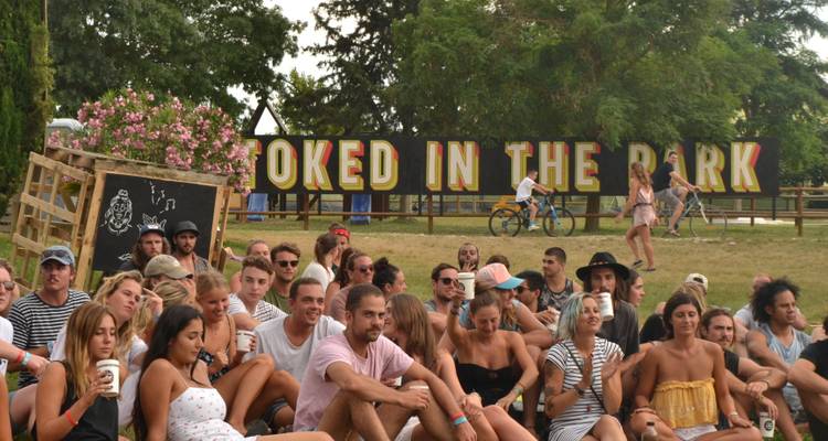 Foule assise à un festival en plein air avec un panneau en arrière-plan