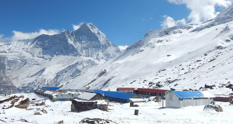 Lodge bedekt met sneeuw met de Machapuchare berg op de achtergrond.
