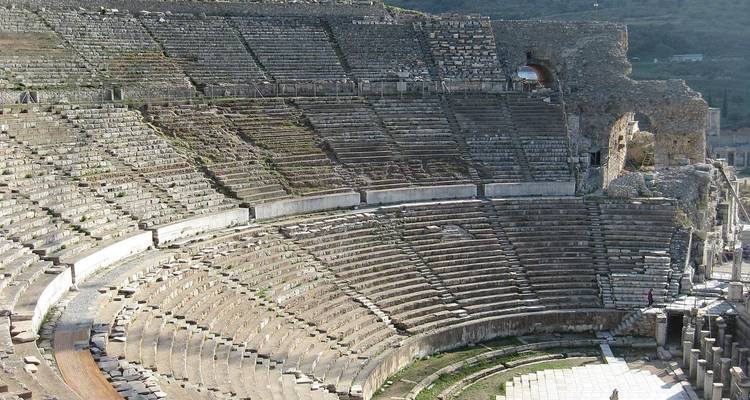 Großes antikes Amphitheater mit Steinsitzen und Ruinen.