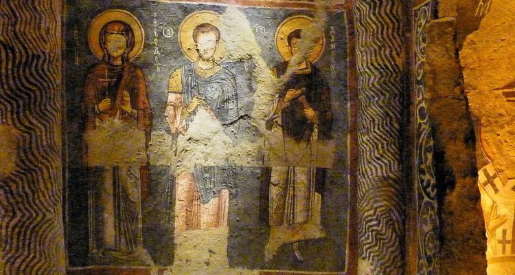 Peintures murales représentant des saints sur un mur de pierre.