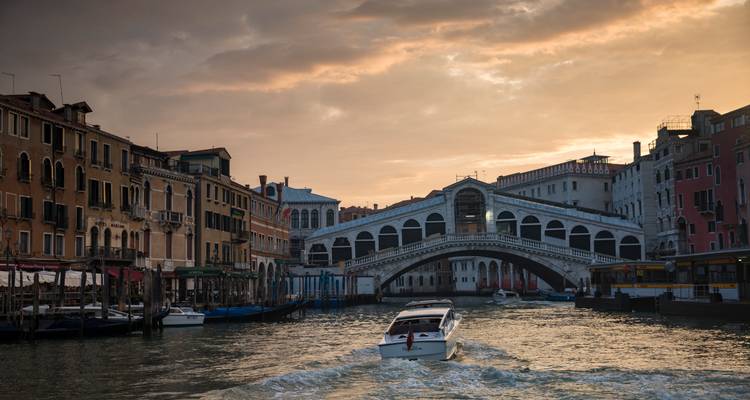 Croisière en bateau descendant le Grand Canal de Venise en direction du pont du Rialto illuminé au coucher du soleil