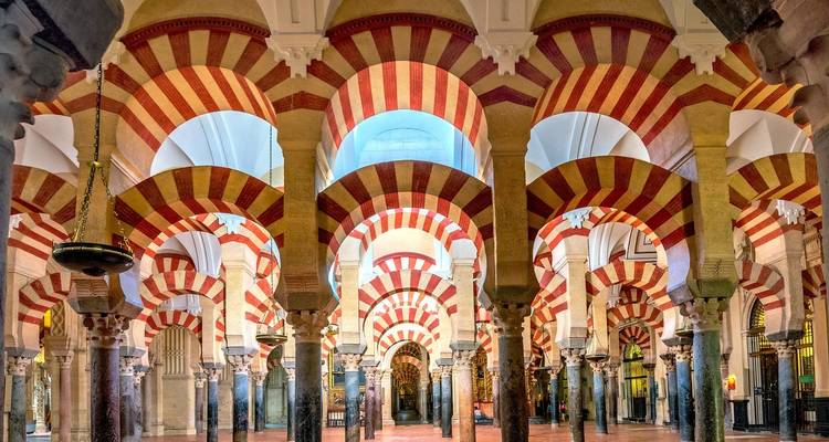 Intérieurs ornés avec des arcs et colonnes rayés dans une mosquée ancienne.