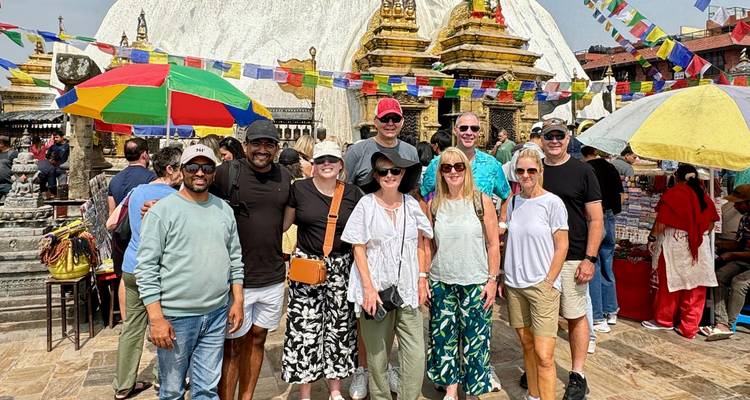 Grupo de turistas frente a una estupa con banderas de oración.