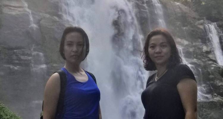Two women standing in front of a large waterfall.
