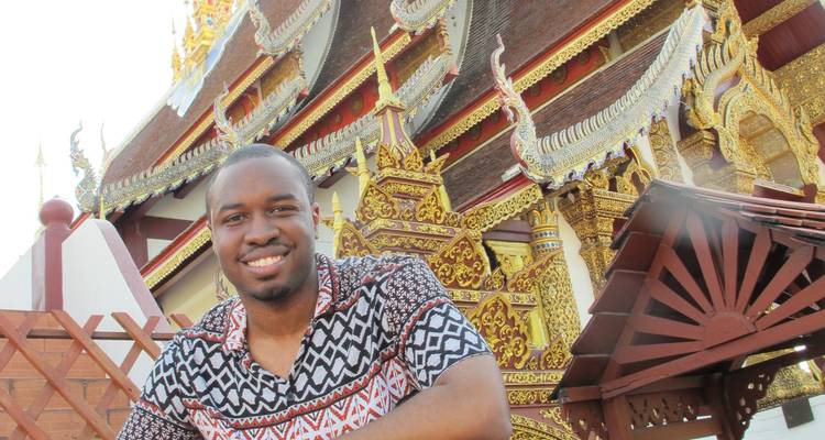 Man smiling in front of an intricately decorated temple.