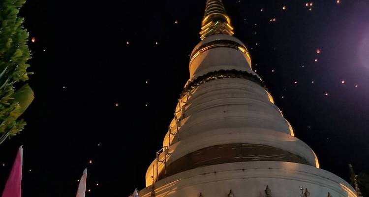 Pagoda under a starry night sky with lanterns.