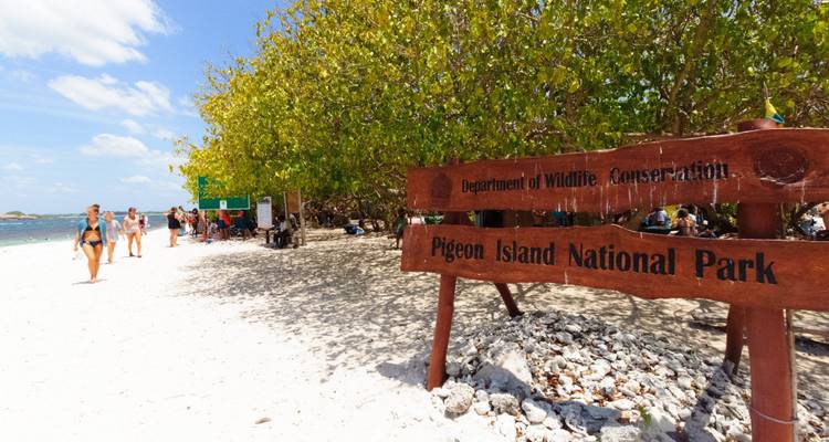 Schild im Pigeon Island Nationalpark mit Menschen, die den Strand genießen.