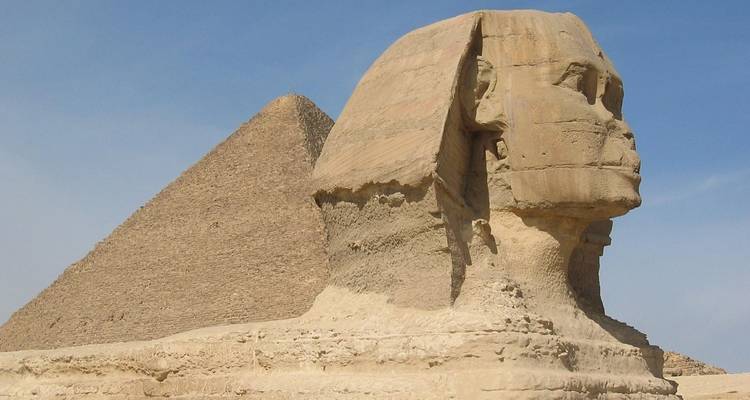 Close up of the Sphinx with a pyramid in the background.