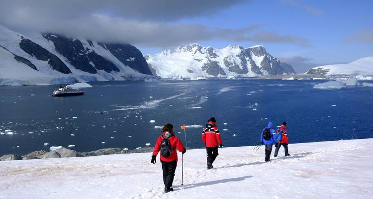 Grupo caminando sobre la nieve con montañas heladas en el fondo