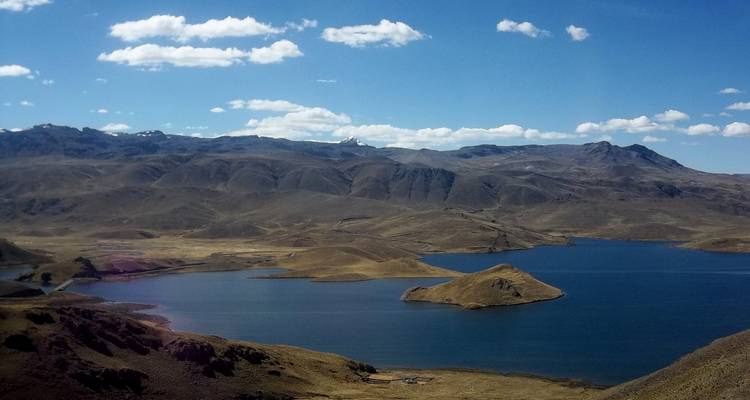 Vista aérea de un lago rodeado de montañas y un cielo azul claro.