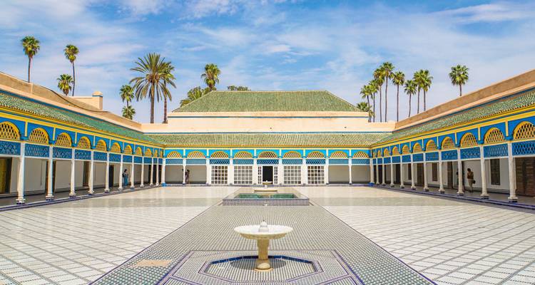 Innenhof mit blauen, gelben arabischen Bögen und einem Brunnen.