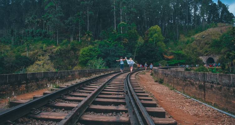 Mensen die over treinrails door het bos lopen.