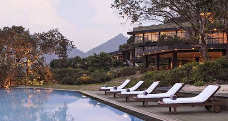 Luxe resort met ligbedden naast een zwembad en bergen.