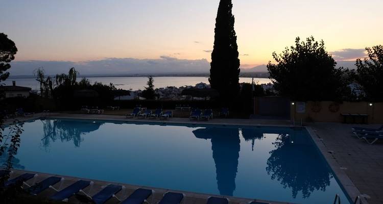 Schwimmbad bei Sonnenuntergang mit malerischem Blick über ein Gewässer.