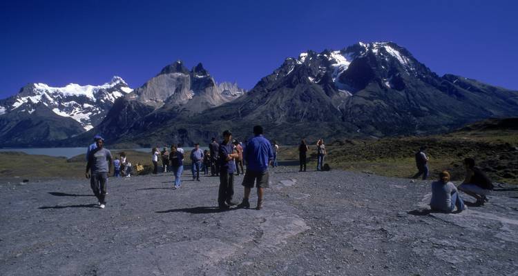 Touristen an einem Aussichtspunkt mit Bergen und See.