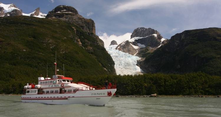 Boot fährt vor Gletschern und üppigen Bergen.