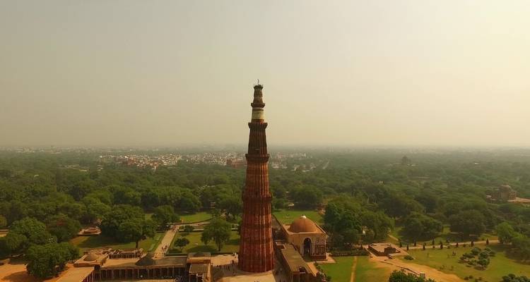 Hoge historische toren omgeven door een groen landschap.