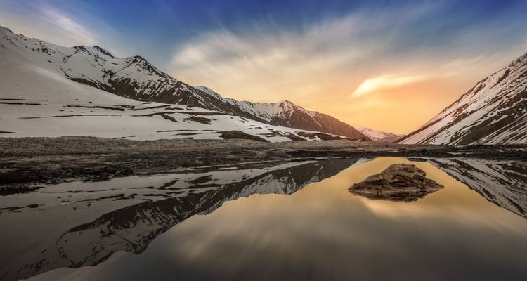 Des montagnes enneigées se reflétant dans un lac serein.