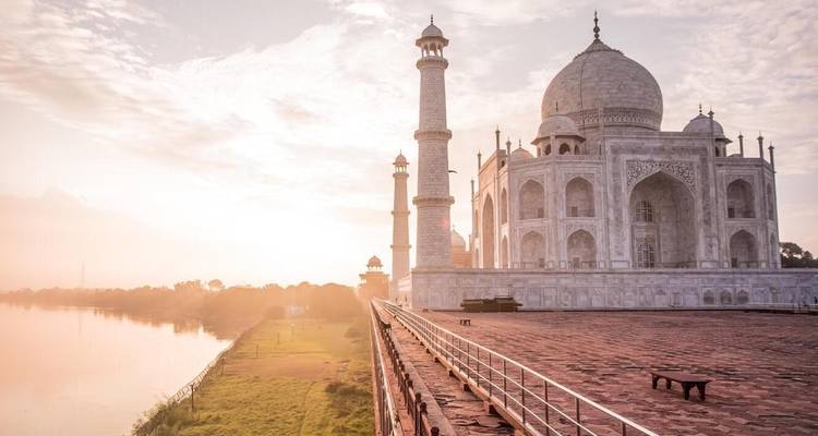 Das Taj Mahal im warmen Sonnenlicht der Morgendämmerung bei klarem Himmel.