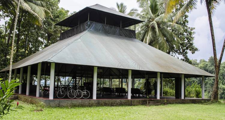 Open-air pavilion with bicycles nearby, in a lush setting.
