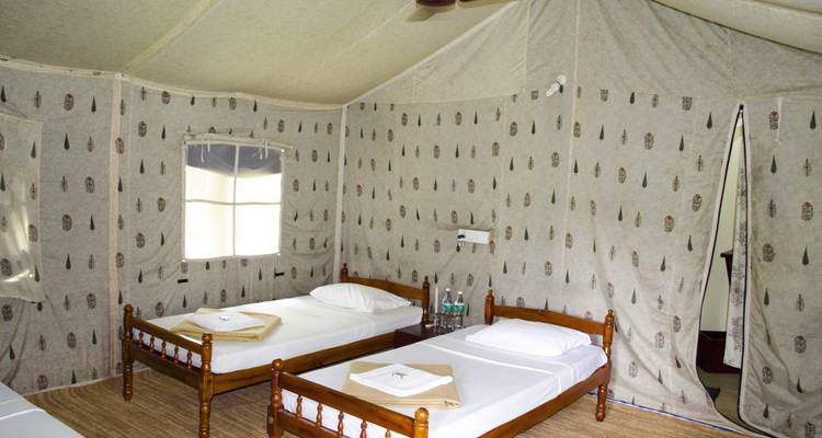 Interior of a tent with wooden beds and small windows.