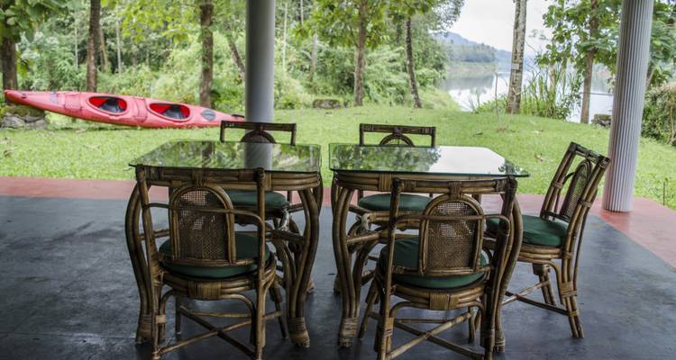 Outdoor dining area with glass-top tables and a kayak on a lawn.