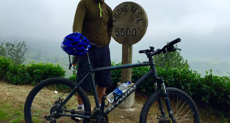 Cycliste debout à côté d'un vélo et d'un panneau indiquant l'altitude.
