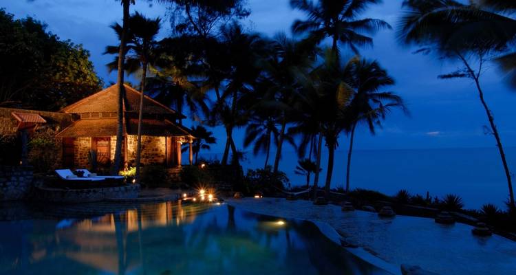 Een nachtbeeld van een resort aan zee met palmbomen.