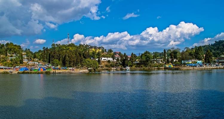 Malerischer See umgeben von bewaldeten Hügeln und klarem Himmel.