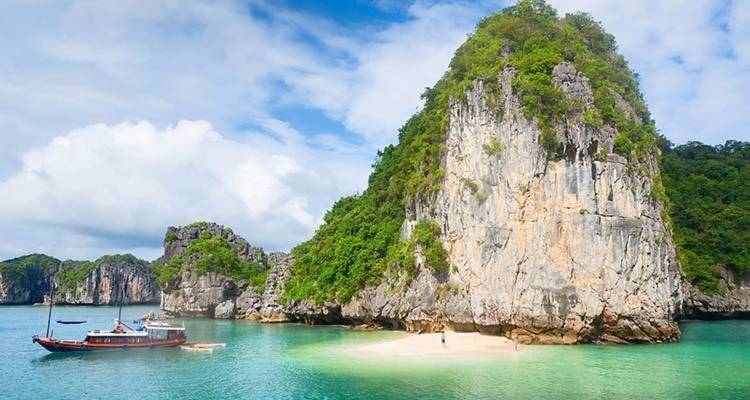 Islote rocoso de piedra caliza rodeado de agua turquesa y una pequeña playa.